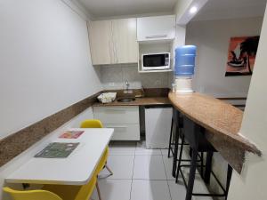 a small kitchen with a counter and a table at Hotel Victory Business Flat Beira Mar Tambaú in João Pessoa