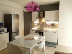 una cocina con una mesa blanca y un colgante rosa en casa vacanze La Formica en Capo dʼOrlando