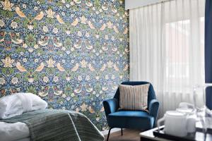 - une chambre avec une chaise bleue et un papier peint floral dans l'établissement Best Western Plus Västerviks Stadshotell, à Västervik