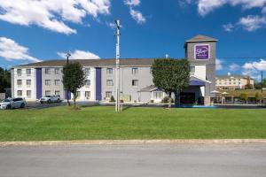 a large white building with a purple sign on it at Sleep Inn & Suites Cullman I-65 exit 310 in Cullman
