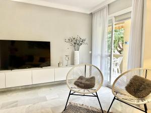 sala de estar con 2 sillas y TV en City Center Marbella Apartment - EaW Homes, en Marbella