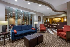 Comfort Suites Perrysburg - Toledo South في بيرسبورغ: غرفة معيشة مع أريكة زرقاء وكرسيين