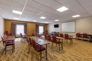 Comfort Suites Perrysburg - Toledo South في بيرسبورغ: قاعة اجتماعات مع طاولات وكراسي وشاشة