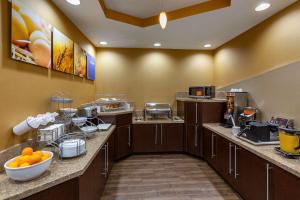 Comfort Suites Perrysburg - Toledo South في بيرسبورغ: مطبخ كبير مع خزائن بنية اللون والبرتقال على المنضدة