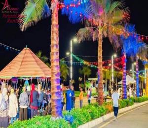 un groupe de personnes se promenant autour d'un festival avec des palmiers dans l'établissement شاليه للايجار اليومى بورتو سعيد, à Port-Saïd