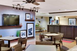 a restaurant with tables and chairs and a flat screen tv at Wingate by Wyndham Cranberry in Cranberry Township