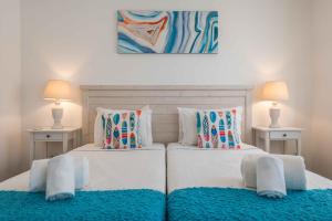 two beds in a bedroom with two tables and two lamps at Casa Mar d'Alma in Albufeira