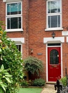a red door on a brick building with a black cat in front at Smart & Comfortable 3-bedroom Victorian house in Stalham