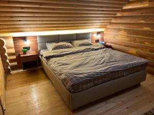 a bed in a room with a wooden wall at Cottage Forest House in Skhidnitsa