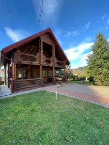 uma cabana de madeira com um relvado à frente em Cottage Forest House em Skhidnitsa