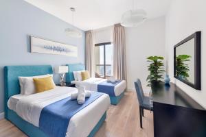 a hotel room with two beds and a tv at Luxury JBR Shams - Sea or Marina View - Free 5 star Beach Resorts Access! in Dubai