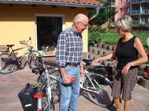 Ein Mann und eine Frau stehen neben einem Fahrrad in der Unterkunft Landguthotel Hotel-Pension Sperlingshof in Dallgow