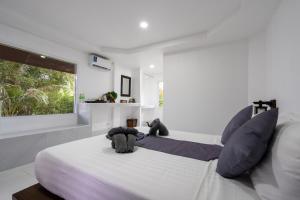 a white bedroom with a large bed with blue pillows at El Matcha Lanta Resort in Phra Ae beach
