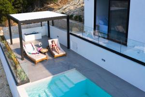 a woman sitting in a chair next to a swimming pool at Mandevilla Hillside Luxury Villas in Agios Nikitas