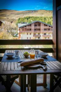 - une table en bois avec de la nourriture sur le balcon dans l'établissement Appartement de 2 chambres a Les Deux Alpes a 100 m des pistes avec balcon et wifi, à Les Deux Alpes