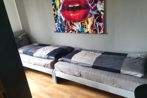 two beds in a room with a painting on the wall at Work & stay apartment with balcony near Ingolstadt in Großmehring