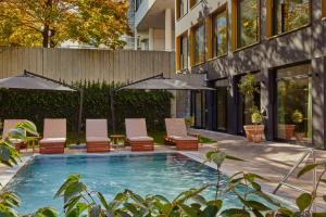 a pool with chairs and umbrellas next to a building at WunderLocke Munich in Munich