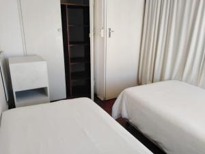 Duas camas num pequeno quarto com duas saias. em Accoustix Backpackers Hostel em Joanesburgo