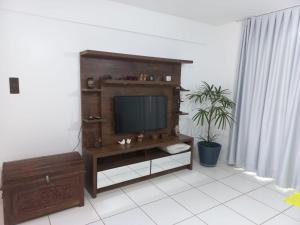 una sala de estar con TV en un centro de entretenimiento de madera en Reserva Imbassaí Vila dos Lirios, en Imbassai