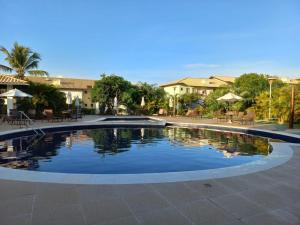 a swimming pool in a courtyard with tables and umbrellas at Reserva Imbassaí Vila dos Lirios in Imbassai