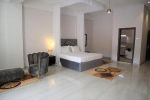 1 dormitorio con 1 cama, 1 silla y 1 sofá en The Voice Hotel, en Entebbe