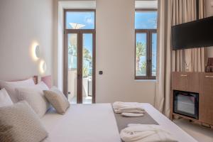 Sala de estar con cama y TV en Omma Suites, en Rethymno