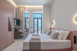 a white bedroom with a large bed and a desk at Omma Suites in Rethymno Town