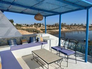 a patio with chairs and a table and a view of the water at Dar Elbidha in Djerba