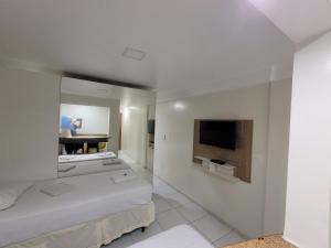 a room with two beds and a tv and a mirror at Hotel Victory Business Flat Beira Mar Tambaú in João Pessoa