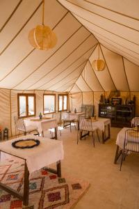 une grande tente avec des tables et des chaises. dans l'établissement Beldi camp, à Merzouga