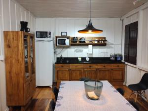 a kitchen with a table and a white refrigerator at Pousada Somenzi, próximo a Miolo, no Vale dos Vinhedos in Bento Gonçalves