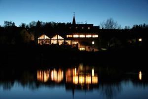 un edificio iluminado por la noche junto a un lago en Gasthof - Pension Krämerhof, en Thanstein