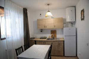 eine Küche mit einem Tisch und einem weißen Kühlschrank in der Unterkunft Cabana de lemn Runcu Stone in Runcu