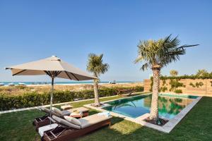 einen Pool mit Stühlen, einem Sonnenschirm und Palmen in der Unterkunft Club Privé By Rixos Saadiyat in Abu Dhabi