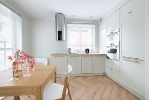 a kitchen with white cabinets and a wooden table at Happy Stay Comfort Apartment By the Beach in Sopot