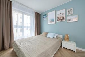 a bedroom with a bed with blue walls and a window at Happy Stay Comfort Apartment By the Beach in Sopot