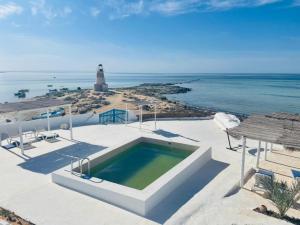a house with a swimming pool and a lighthouse at Dar Elbidha in Djerba