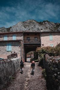 dos personas montando bicicletas por un camino delante de un edificio en Le Bezy Pyrénées, en Mézerville