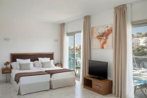 a bedroom with a bed and a flat screen tv at Porto Drach Aparthotel & Suites in Porto Cristo