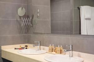 a bathroom with two sinks and a mirror at Porto Drach Aparthotel & Suites in Porto Cristo