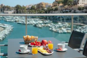 a table with a bowl of fruit and a basket of juice at Porto Drach Aparthotel & Suites in Porto Cristo