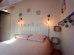a bedroom with a bed with white sheets and lights at DUPLEX les pieds dans l' eau in Jullouville-les-Pins
