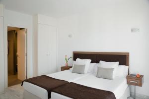 a bedroom with a large bed with white sheets and pillows at Porto Drach Aparthotel & Suites in Porto Cristo