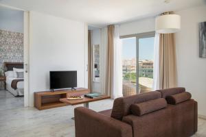 a living room with a couch and a television at Porto Drach Aparthotel & Suites in Porto Cristo