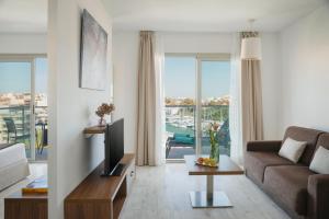 a living room with a couch and a tv at Porto Drach Aparthotel & Suites in Porto Cristo