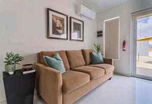 a living room with a brown couch with blue pillows at Bida Marino Residence Aruba in Palm-Eagle Beach