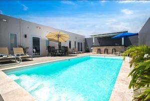 - une piscine d'eau bleue en face d'une maison dans l'établissement Bida Marino Residence Aruba, à Palm-Eagle Beach