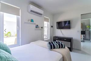 a white bedroom with a bed and a tv at Bida Marino Residence Aruba in Palm-Eagle Beach