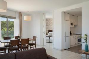 a living room and kitchen with a table and chairs at Porto Drach Aparthotel & Suites in Porto Cristo