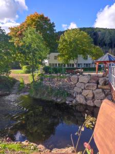 a stone wall next to a river with a bench at Suite Am Radweg in Pittenbach